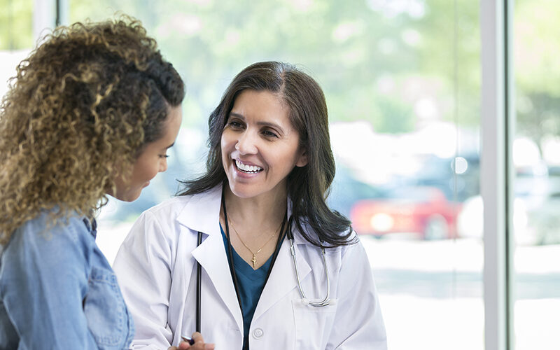 Female doctor discusses something with young mixed race patient